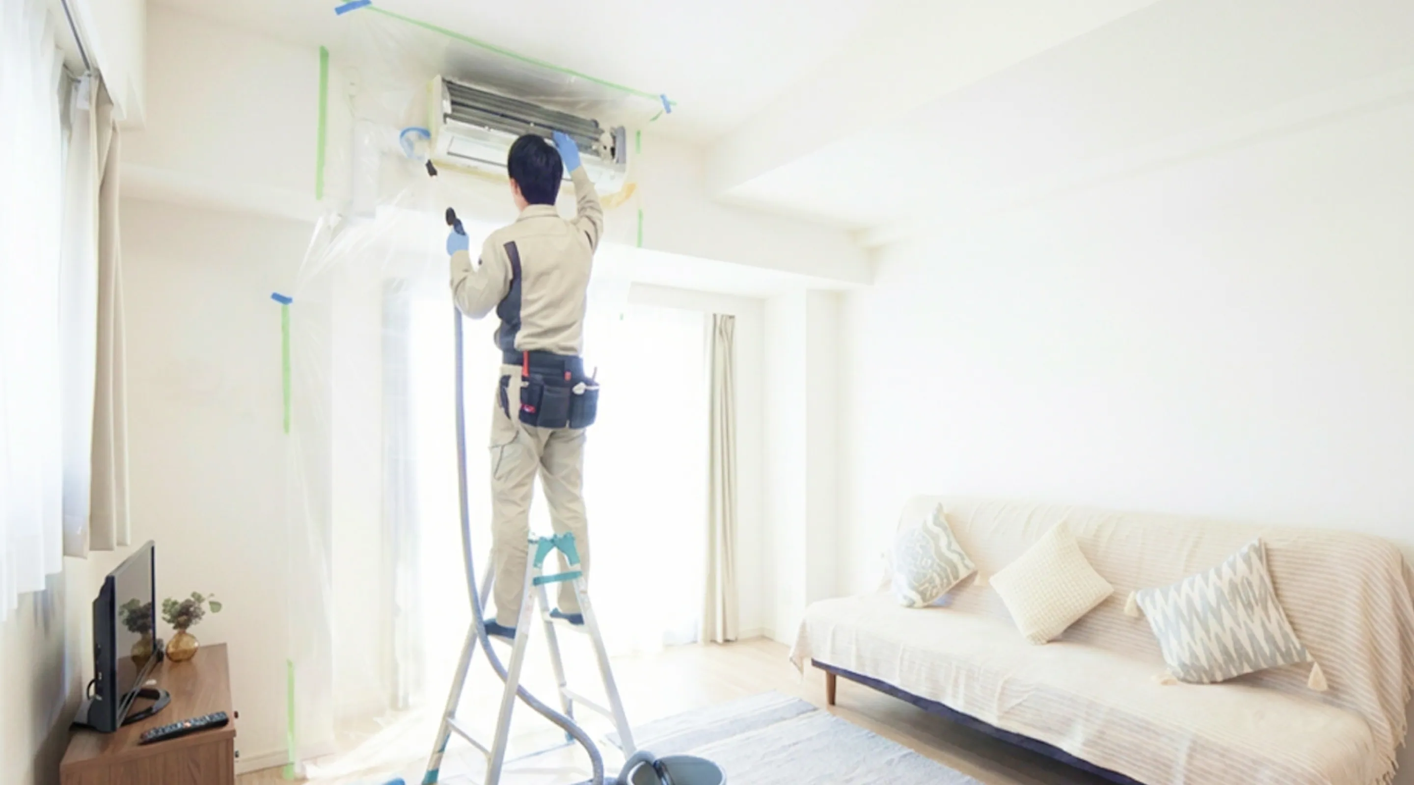 作業員がエアコン点検している写真